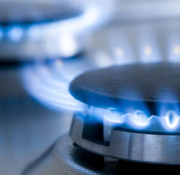 Du siehst eine Gasflamme auf einem silbernen Herd mit blauer, sauberer Verbrennung im Nahaufnahme.