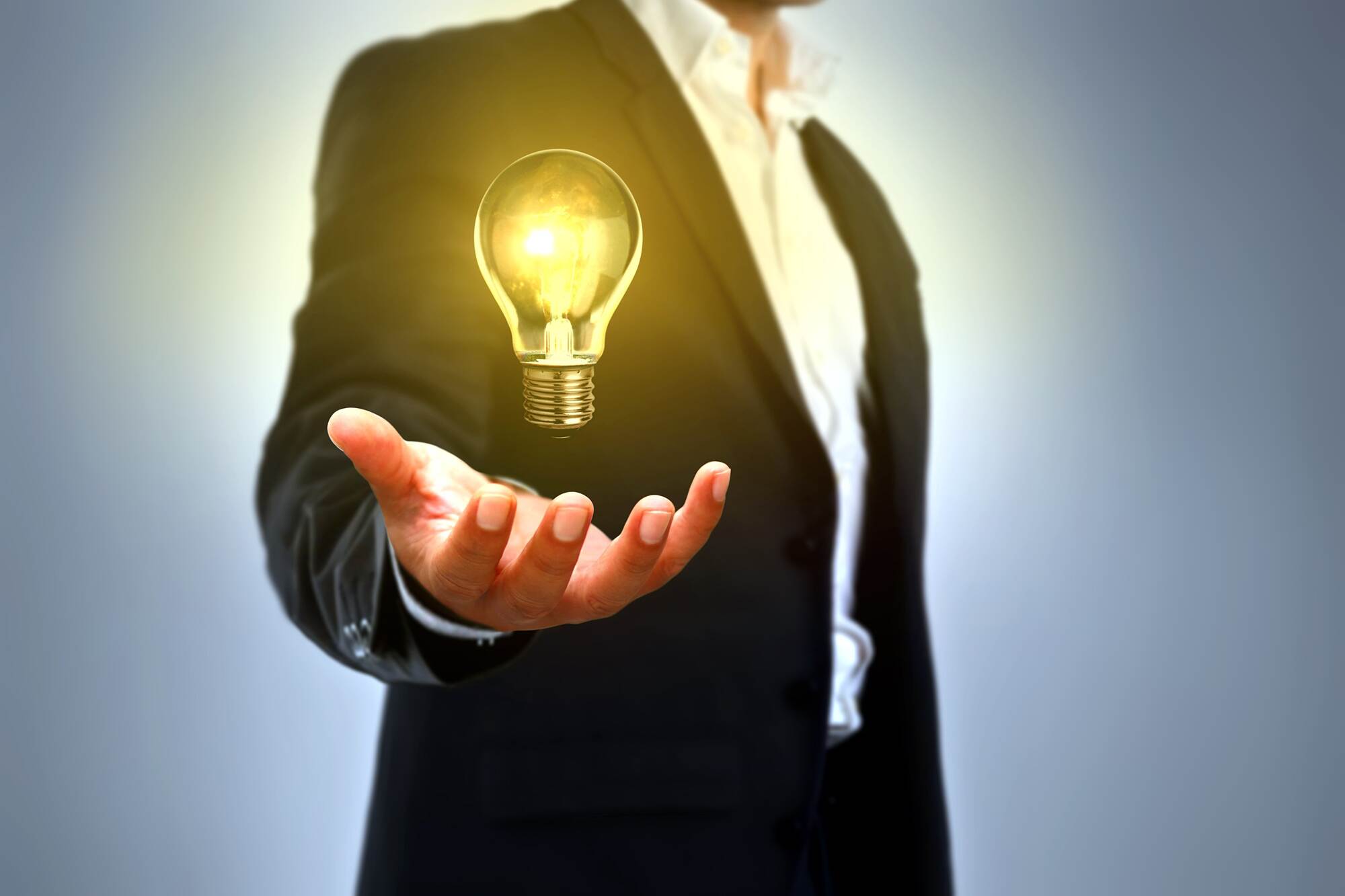 Collage: Rumpf eines Mannes mit ausgetreckter Hand, darüber schwebt eine leuchtende Glühlampe